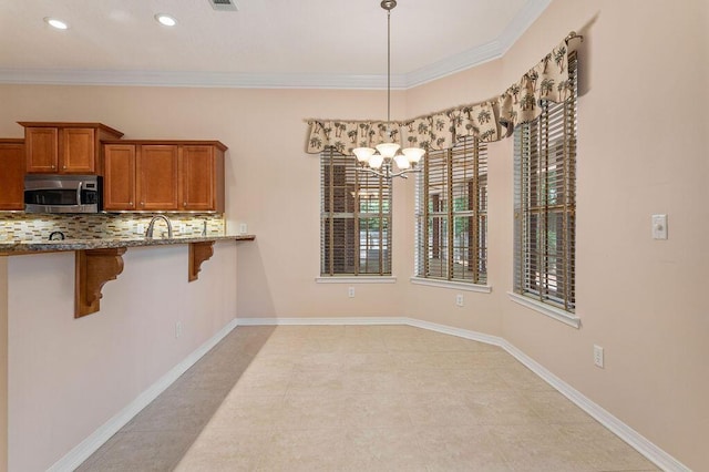unfurnished dining area featuring a chandelier, crown molding, a sink, recessed lighting, and light tile patterned floors
