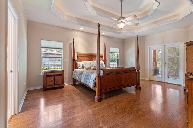 bedroom featuring access to outside, a raised ceiling, multiple windows, light wood finished floors, and recessed lighting