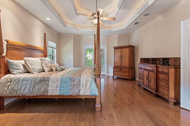 bedroom with wood finished floors, a raised ceiling, recessed lighting, and a ceiling fan