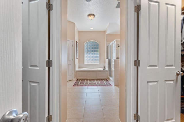 hallway with light tile patterned flooring and a textured ceiling