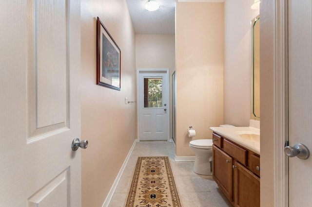bathroom featuring vanity, toilet, baseboards, and tile patterned floors