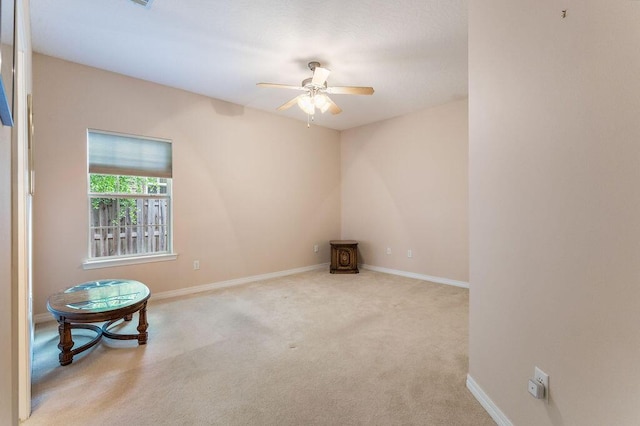 carpeted empty room with a ceiling fan and baseboards