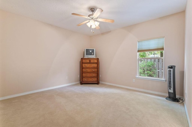 carpeted empty room with a ceiling fan and baseboards