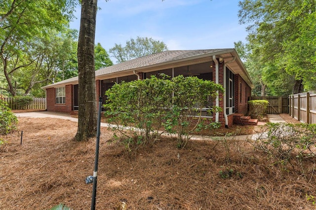 view of front facade with brick siding, a fenced backyard, and a sunroom
