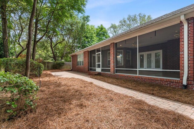 back of property featuring brick siding, a sunroom, and fence