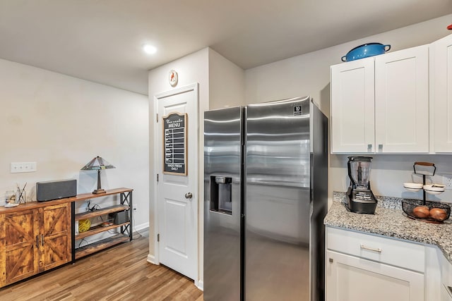 kitchen with light stone countertops, light wood-style flooring, recessed lighting, white cabinetry, and stainless steel refrigerator with ice dispenser