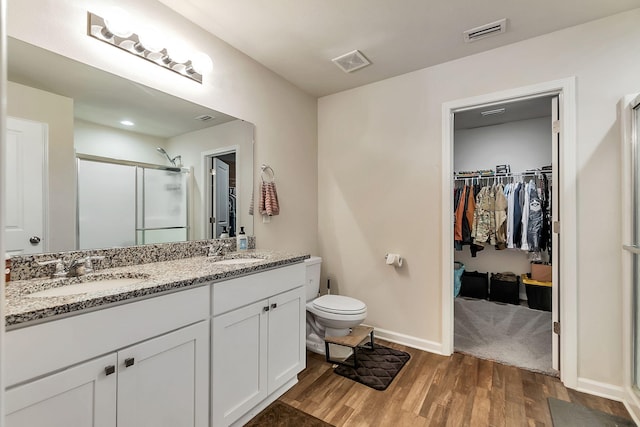 bathroom featuring a sink, a stall shower, wood finished floors, and visible vents