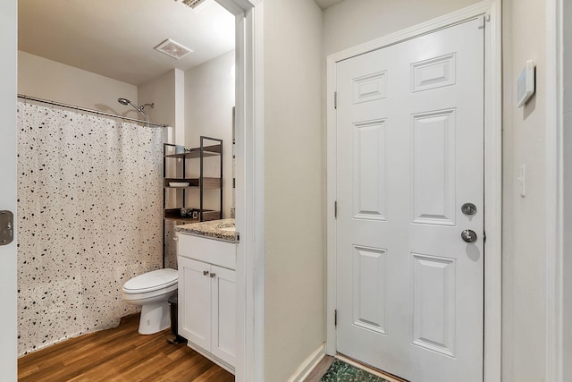 bathroom with a shower with curtain, visible vents, wood finished floors, vanity, and toilet