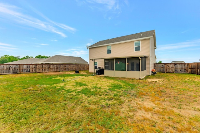 rear view of property with a fenced backyard, a yard, and a sunroom