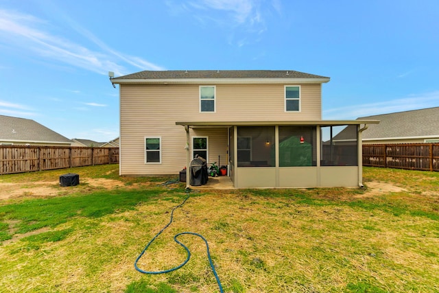 rear view of house with a yard, a fenced backyard, and a sunroom