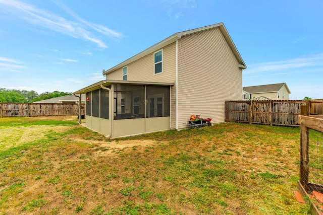 rear view of house featuring a lawn, a fenced backyard, and a sunroom