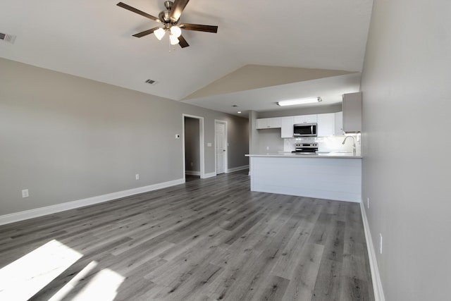 unfurnished living room featuring baseboards, ceiling fan, vaulted ceiling, and visible vents