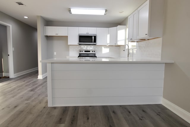 kitchen featuring a sink, stainless steel appliances, baseboards, backsplash, and visible vents