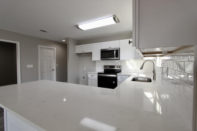 kitchen with electric stove, a sink, stainless steel microwave, and light stone countertops