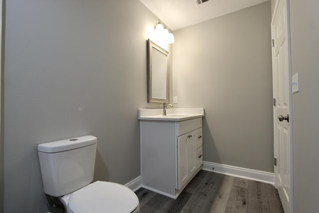 bathroom featuring baseboards, wood finished floors, toilet, and vanity