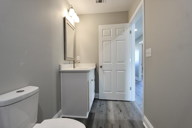 bathroom featuring visible vents, wood finished floors, vanity, baseboards, and toilet