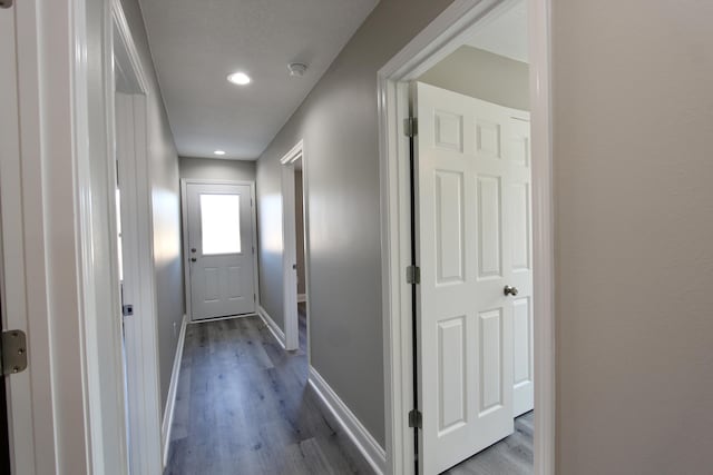 corridor with dark wood-style flooring, baseboards, and recessed lighting