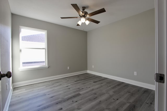 unfurnished room with a ceiling fan, baseboards, and dark wood-type flooring