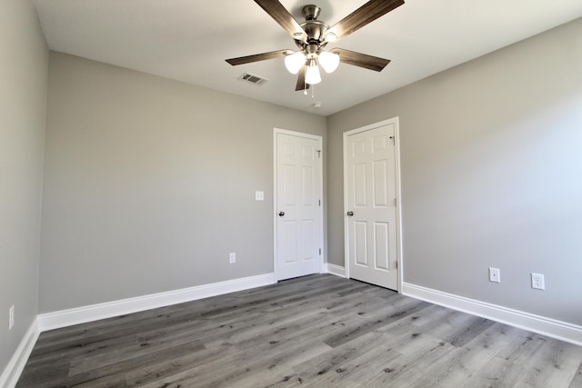 unfurnished bedroom with ceiling fan, baseboards, visible vents, and wood finished floors