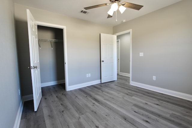 unfurnished bedroom with visible vents, a closet, wood finished floors, baseboards, and ceiling fan