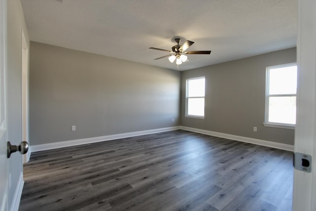 unfurnished room with a ceiling fan, baseboards, and dark wood finished floors