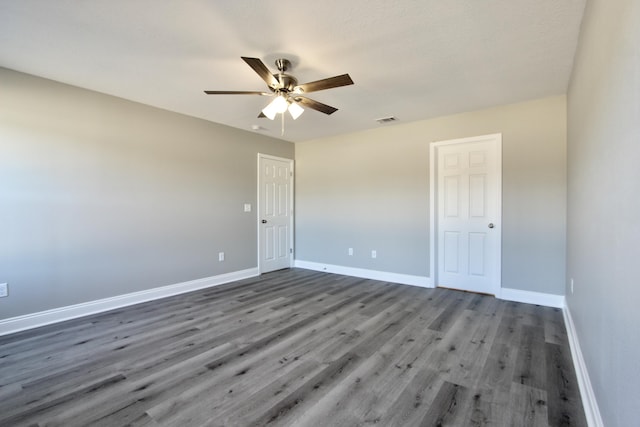 spare room with baseboards, a ceiling fan, wood finished floors, and visible vents