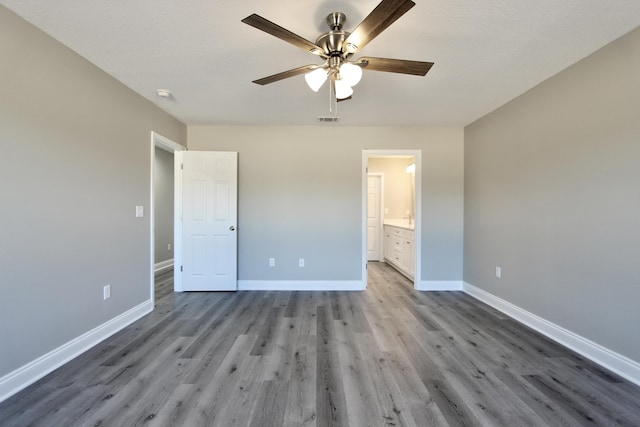 unfurnished bedroom featuring a ceiling fan, baseboards, visible vents, and wood finished floors