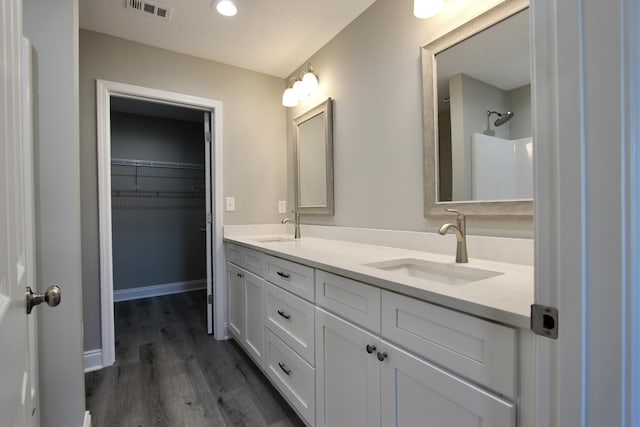 bathroom featuring a sink, double vanity, wood finished floors, and visible vents