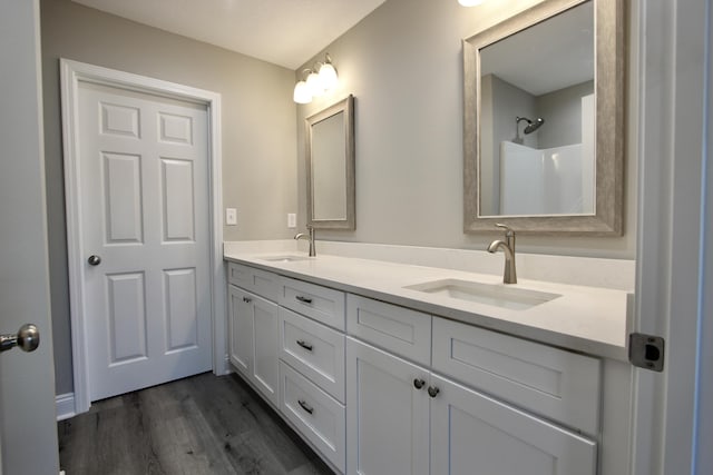 bathroom with double vanity, a sink, and wood finished floors