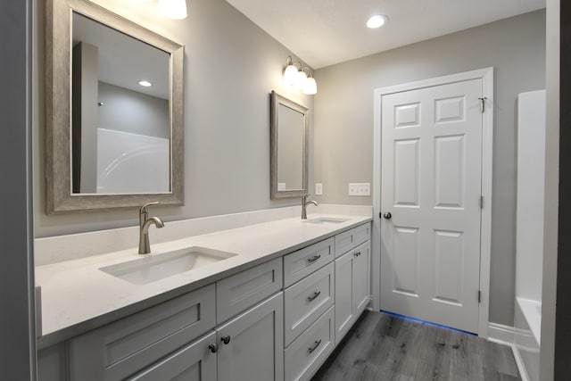full bathroom featuring double vanity, a sink, wood finished floors, and recessed lighting