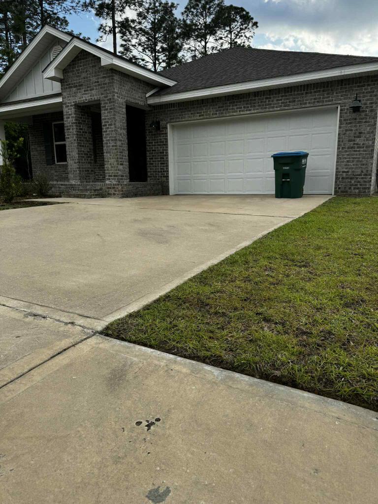 6620 Spyglass Hill Rd, Laurel Hill, FL 32567 - view of front of property with board and batten siding, a garage, brick siding, a front lawn, and concrete driveway