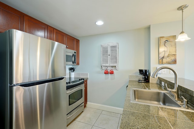 kitchen featuring a sink, light tile patterned floors, baseboards, tile counters, and stainless steel appliances