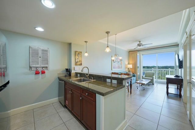 kitchen with tile countertops, hanging light fixtures, a sink, baseboards, and a peninsula