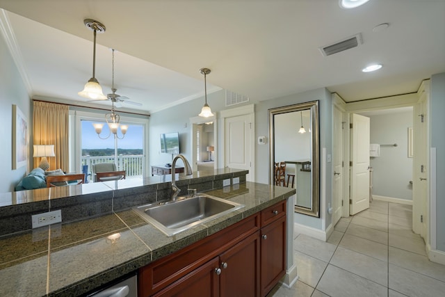 kitchen with crown molding, a sink, tile counters, visible vents, and pendant lighting