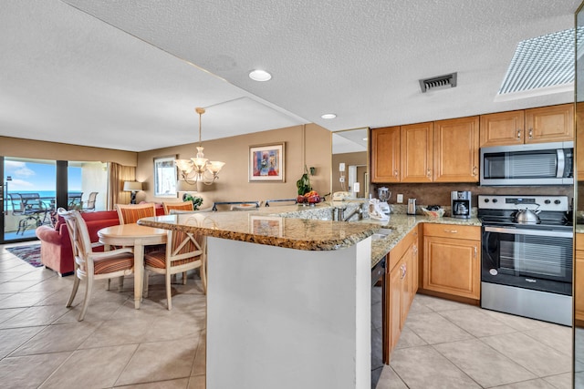 kitchen featuring stainless steel appliances, a chandelier, a textured ceiling, light stone counters, and light tile patterned floors