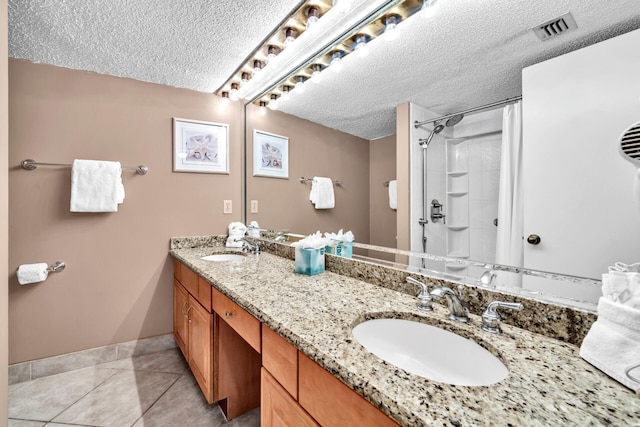 full bath featuring a textured ceiling, a shower with curtain, baseboards, tile patterned floors, and double vanity