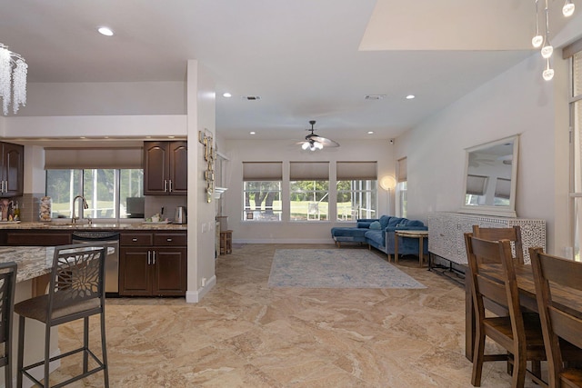 674 Emerald Bay Dr, Destin, FL 32541 - kitchen with dishwashing machine, a sink, ceiling fan, dark brown cabinets, and light stone countertops