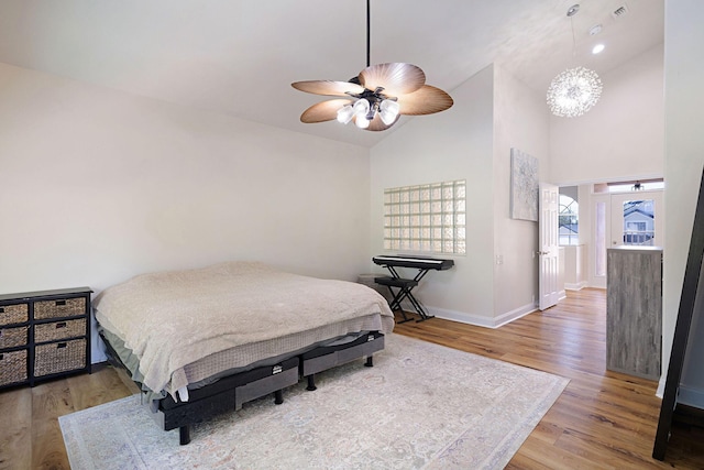 674 Emerald Bay Dr, Destin, FL 32541 - bedroom featuring wood finished floors, baseboards, high vaulted ceiling, a ceiling fan, and a chandelier