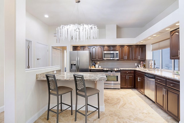 674 Emerald Bay Dr, Destin, FL 32541 - kitchen with appliances with stainless steel finishes, a sink, a kitchen bar, dark brown cabinetry, and a peninsula