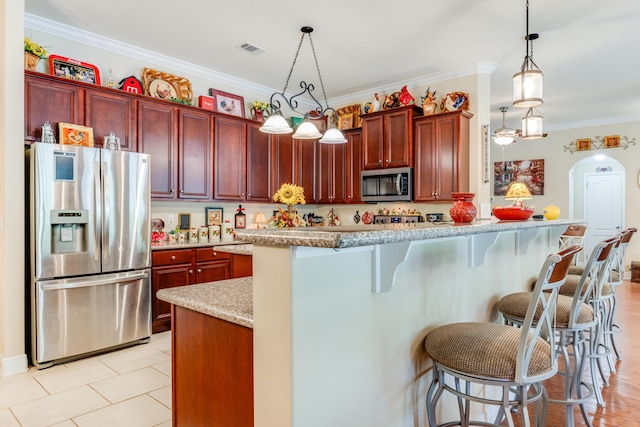 6444 Welannee Blvd, Laurel Hill, FL 32567 - kitchen with stainless steel appliances, reddish brown cabinets, crown molding, and pendant lighting