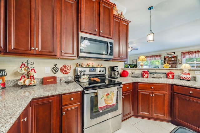 6444 Welannee Blvd, Laurel Hill, FL 32567 - kitchen featuring appliances with stainless steel finishes, reddish brown cabinets, light tile patterned floors, decorative light fixtures, and light stone counters