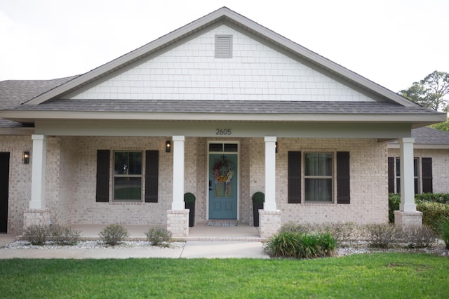 view of front of property with roof with shingles, covered porch, and brick siding