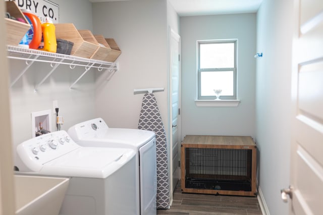 laundry room featuring washing machine and clothes dryer, laundry area, a sink, and wood finished floors