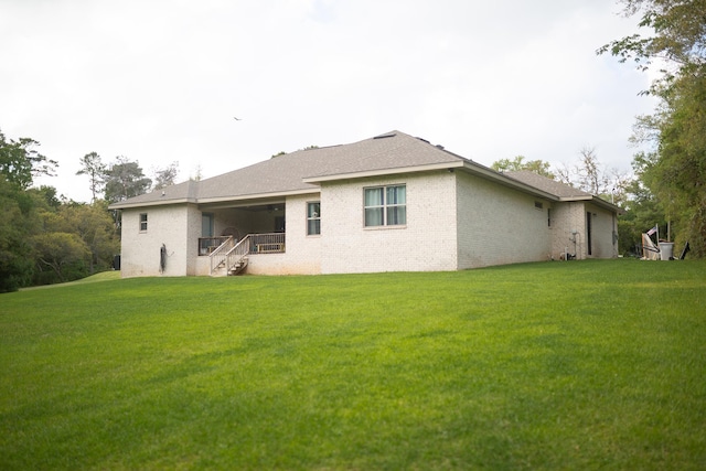 back of house with stairs, a yard, and brick siding