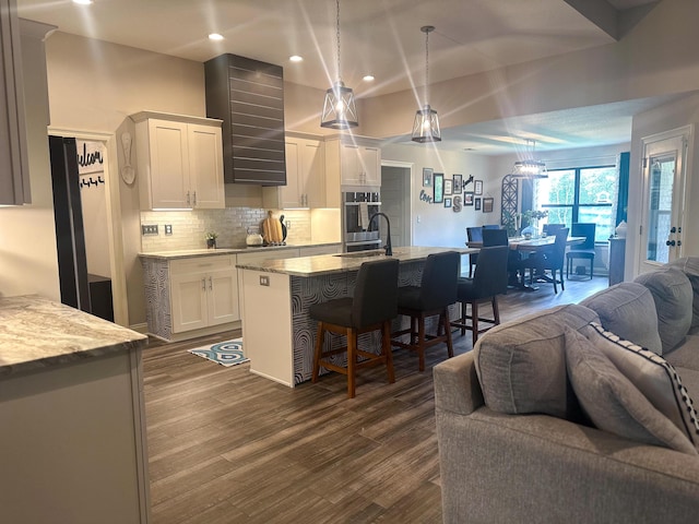 kitchen with a breakfast bar, oven, open floor plan, white cabinets, and backsplash