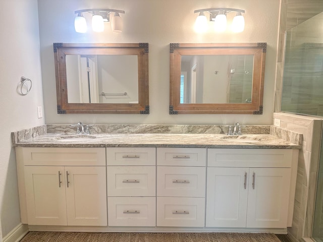 full bath with a sink, an enclosed shower, and double vanity