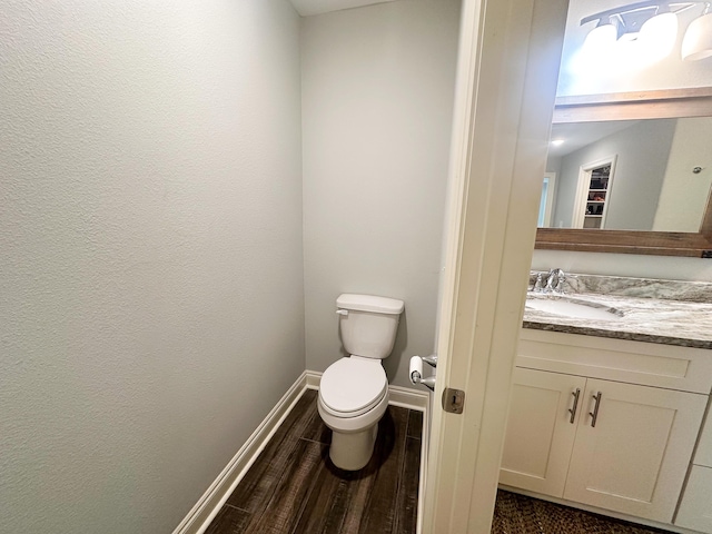 bathroom with baseboards, wood finished floors, toilet, and vanity