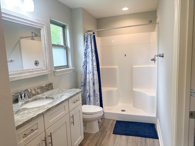 bathroom featuring a stall shower, wood finished floors, vanity, toilet, and recessed lighting