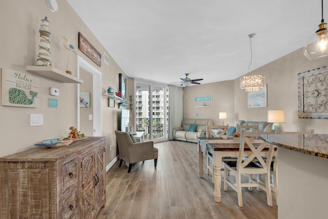 dining area with baseboards, light wood-style floors, visible vents, and ceiling fan with notable chandelier