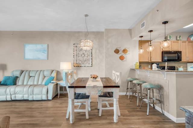 dining area with an inviting chandelier, baseboards, visible vents, and wood finished floors